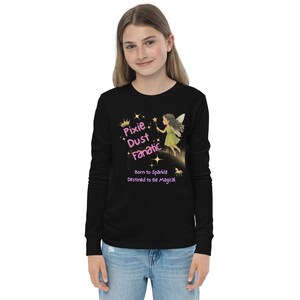 May include: Black long-sleeve shirt with the text "Pixie Dust Fanatic" in pink and gold. A graphic of a fairy with a wand and stars is also featured. The shirt also has the text "Born to Sparkle, Destined to Be Magical."