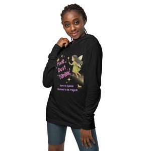 May include: Black long-sleeve hooded shirt with a graphic of a fairy and the text "Pixie Dust Fanatic". The fairy is wearing a green dress and holding a star. The text "Born to Sparkle, Destined to Be Magical" is also on the shirt.