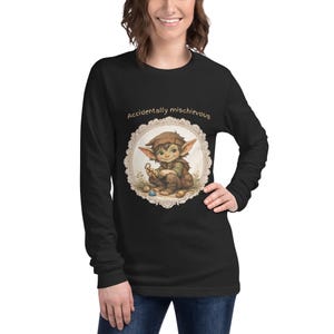 May include: Black long-sleeve shirt featuring a whimsical illustration of a cartoon elf with the text "Accidentally mischievous." The elf is depicted in shades of brown and green, surrounded by a decorative border. The shirt is made of a soft material.