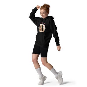 May include: Black hoodie with a graphic on the front. The graphic features a cartoon character with the text "I really care". The person is wearing black shorts, white socks, and white sneakers.