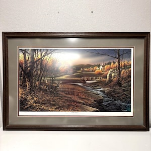 May include: Framed print of a painting depicting a rural scene with a small town in the distance, a stream flowing through a wooded area, and two deer in the foreground. The painting is titled "To Love Nature".