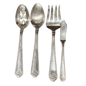 May include: A set of four silver-toned serving utensils: a slotted spoon, a solid spoon, a fork, and a butter knife. Each piece has a decorative handle with a detailed floral design at the base. The utensils are arranged against a white background.