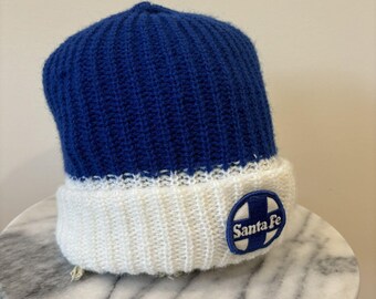 May include: Blue and white knit beanie with a Santa Fe logo patch.