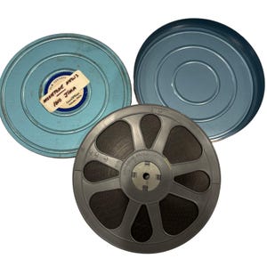 May include: Vintage film reel with a label reading "Movietone News Iwo Jima" inside a light blue metal container. The reel is gray and has a dark film strip. The container lid is also light blue.