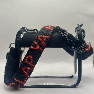Bolso bandolera aprobado por el estadio Cear con correa de cuentas "CLAP YA HANDS" en negro, dorado y rojo