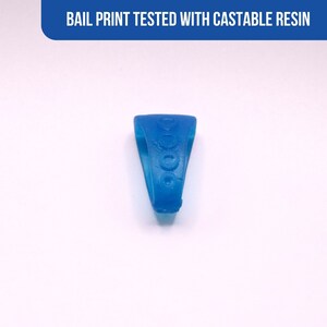 Peut inclure: Une bague bleu vif avec un motif de cercles. La bague est pos&eacute;e sur un fond blanc. Le texte "BAIL PRINT TESTED WITH CASTABLE RESIN" est affich&eacute; dans une banni&egrave;re bleue en haut.