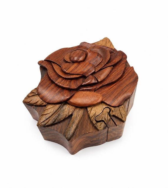 A hand-carved wooden rose puzzle box where the secret opening mechanism is hidden within the floral design — equal parts functional jewelry box and tactile brain teaser.