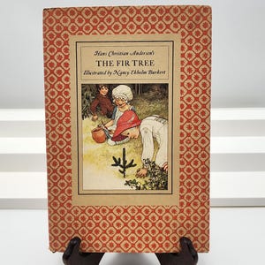 May include: A vintage copy of "The Fir Tree" by Hans Christian Andersen, illustrated by Nancy Ekholm Burkert. The book cover features a detailed illustration with a red and gold patterned border and a scene from the story.