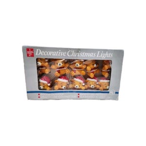 May include: A box of decorative Christmas lights featuring small, plush bear figures. The bears are wearing red Santa hats and scarves. The box reads "Decorative Christmas Lights" and includes text about indoor/outdoor use and safety.
