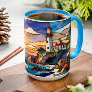 May include: A ceramic coffee mug with a lighthouse design. The mug features a blue handle and rim, and the lighthouse scene is rendered in vibrant colors. The mug is filled with coffee and sits on a wooden cutting board.