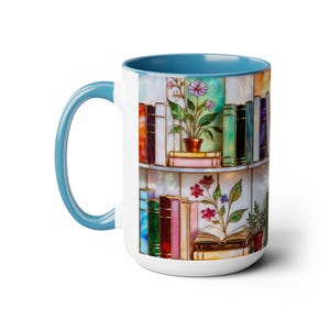 May include: White ceramic mug with a light blue interior and handle. The mug features a colourful illustration of a bookshelf with books and potted plants. The design has a stained glass effect.