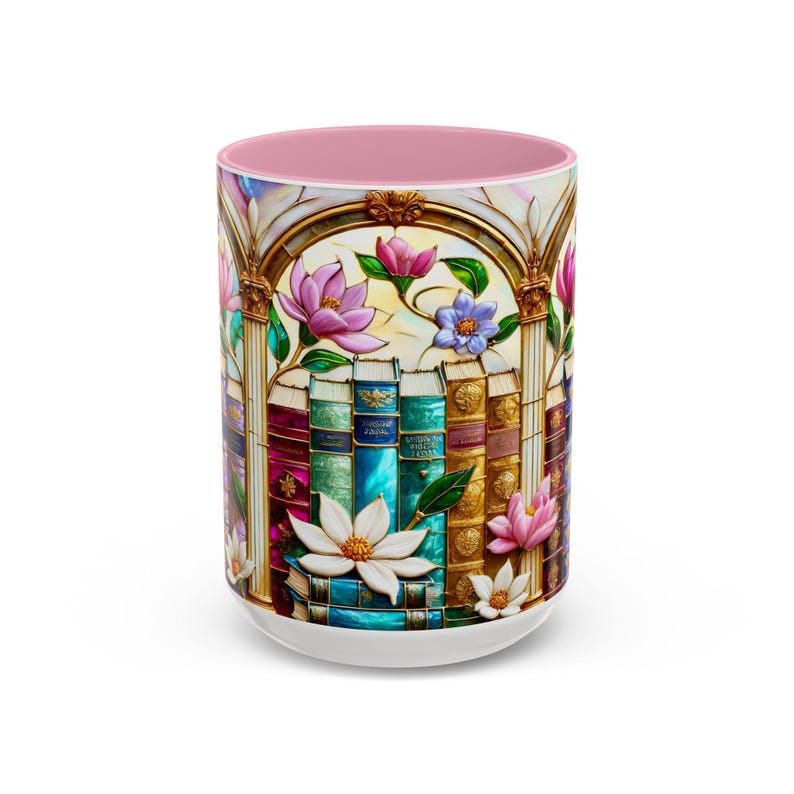 May include: White ceramic mug with a pink interior, featuring a stained-glass design of books, flowers, and an arched window. The design includes pink, blue, and white flowers, and the books have gold accents. The mug has a white base.