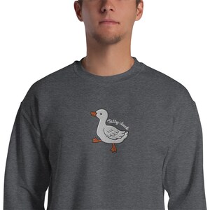 May include: A dark gray sweatshirt with an embroidered white duck with orange feet and the text "Silly duck" in white.