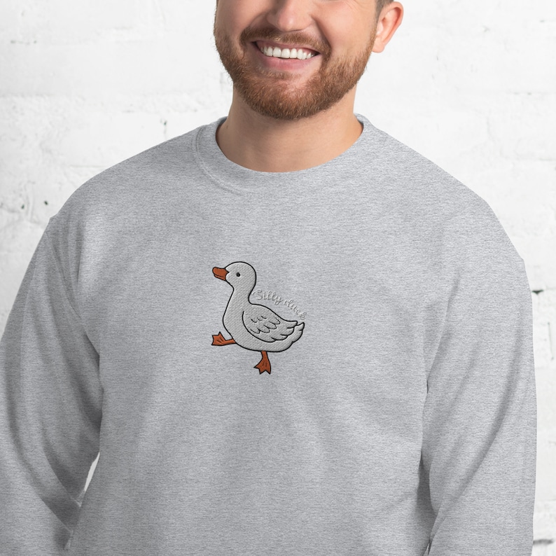 May include: A gray sweatshirt with a cartoon illustration of a white duck with orange feet and the text "Silly Duck" on the front.
