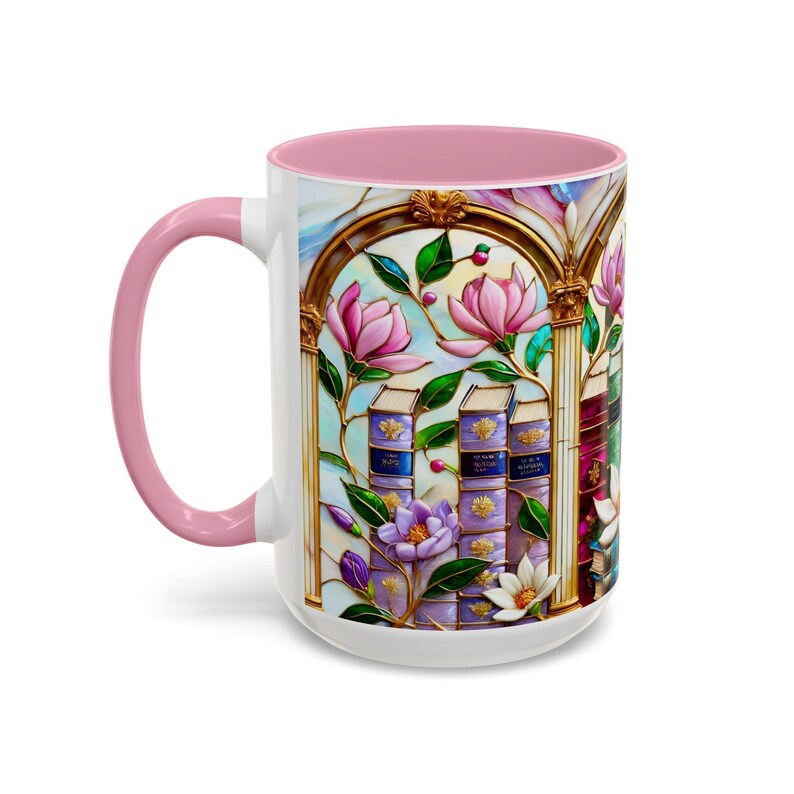 May include: White ceramic mug with a pink interior and handle. The mug features a stained-glass style design with pink magnolia flowers, purple books, and gold accents. The design wraps around the mug.