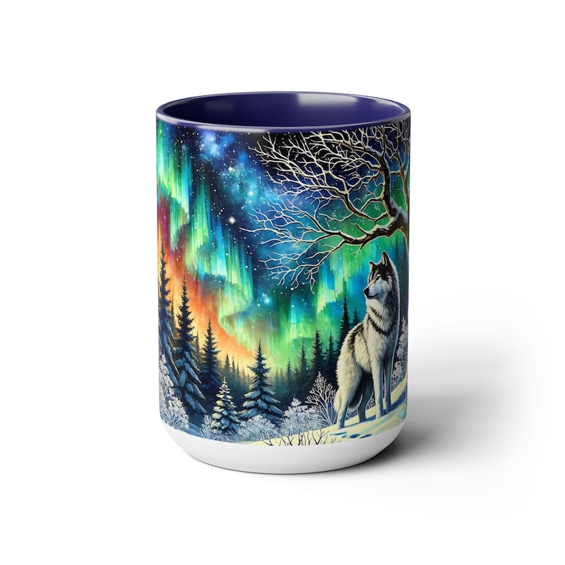Peut inclure: Mug en c&eacute;ramique blanche avec une illustration d'un loup dans une for&ecirc;t enneig&eacute;e sous une aurore bor&eacute;ale. L'int&eacute;rieur du mug est bleu fonc&eacute; et pr&eacute;sente un design enveloppant avec des tons verts, oranges et bleus.