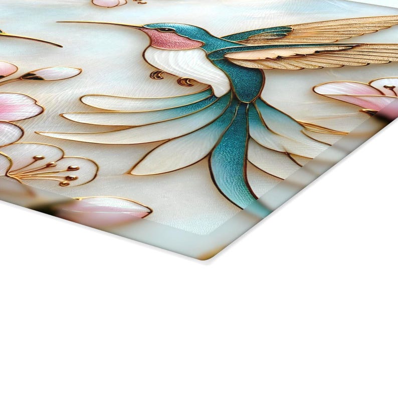 Pode incluir: Pe&ccedil;a de arte decorativa com um beija-flor com plumagem azul, branca e rosa, acentuada com detalhes dourados. O design inclui flores estilizadas em rosa e branco. A obra de arte est&aacute; em um fundo claro.