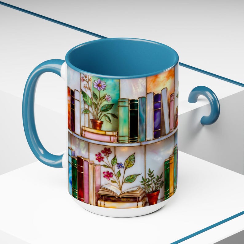 May include: A ceramic coffee mug with a blue handle and interior. The mug features a colourful illustration of a bookshelf with books and potted plants. The design includes various colours, including blue, green, pink, and orange.