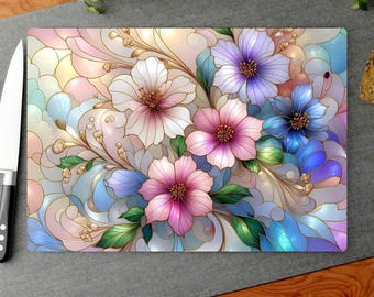May include: Rectangular cutting board with a floral design. The board features a colorful stained-glass style pattern of flowers in shades of pink, purple, blue, and white. The board measures 11 inches by 15 inches.