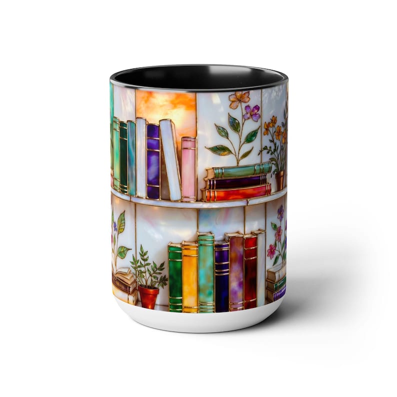 May include: White ceramic mug with a black interior, depicting a colourful bookshelf design with books and flowers. The books have various coloured spines, and the flowers are in shades of purple, orange, and green.