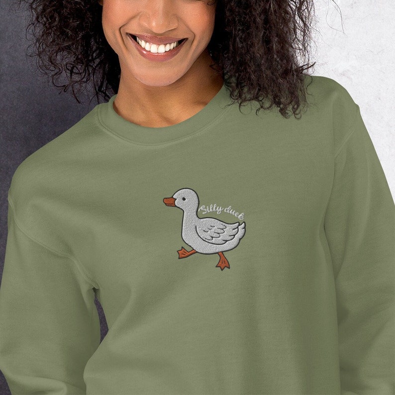 May include: A green sweatshirt with a white embroidered duck and the text "Silly duck" in orange.