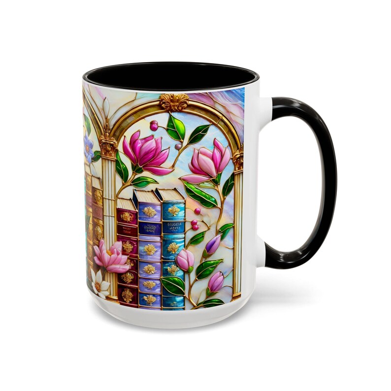 May include: White ceramic mug with a black handle and interior. The mug features a stained-glass design with pink magnolia flowers, books, and gold accents. The design is set against a light blue and white background.