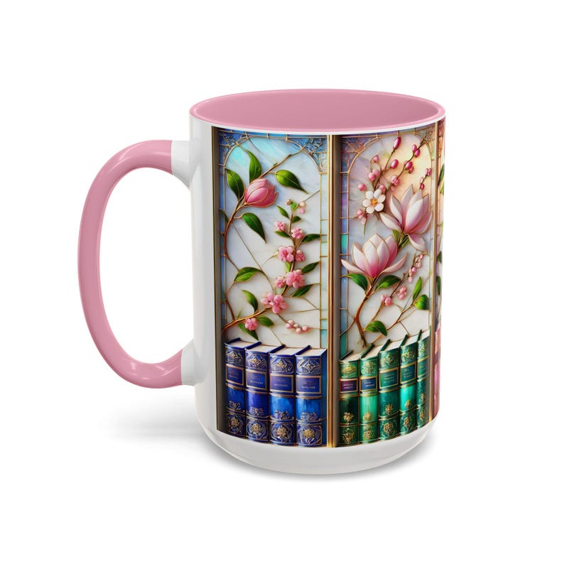 May include: White ceramic mug with a pink handle and interior. The mug features a stained-glass design with pink flowers, green leaves, and a stack of books. The design is framed in gold.