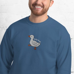 May include: A blue sweatshirt with a white embroidered duck and the text "Silly duck" in brown.