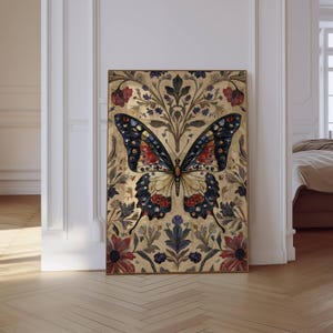 Puede incluir: Una impresi&oacute;n art&iacute;stica enmarcada de una mariposa. La mariposa tiene un cuerpo crema y alas con detalles rojos, azules y negros. El fondo es de color dorado con patrones florales y de hojas. La obra de arte se exhibe en una habitaci&oacute;n con piso de madera.