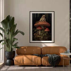 May include: A framed print of a frog sitting on a red and white mushroom in a forest setting.