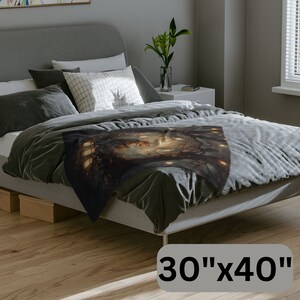 K&ouml;nnte beinhalten: Eine dunkel gef&auml;rbte Decke mit einem Fantasy-Kunstdesign, das eine detaillierte Illustration einer mystischen Szene zeigt. Die Decke misst 76 cm x 102 cm und ist &uuml;ber einem Bett mit grauer Bettw&auml;sche drapiert. Das Kunstwerk enth&auml;lt warme T&ouml;ne und komplizierte Details.