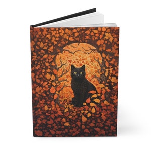 May include: A black cat with yellow eyes sits in a circle of orange and brown leaves. The cat is looking directly at the viewer. The background is a dark orange and brown colour.