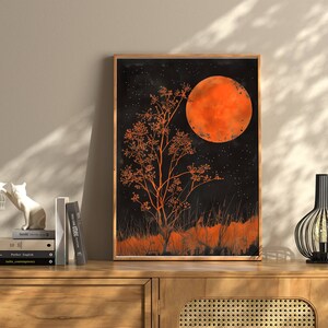 Peut inclure: Une impression encadr&eacute;e d'une peinture &agrave; l'aquarelle noire et orange d'un arbre avec une grande lune orange en arri&egrave;re-plan.