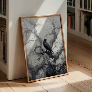 K&ouml;nnte beinhalten: Eine gerahmte Schwarzwei&szlig;illustration eines Rabens, der auf einem Ast eines kahlen Baumes sitzt. Der Hintergrund ist hellgrau mit einem Hauch von Blau.