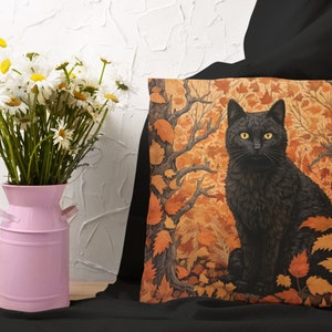 Pu&ograve; includere: Un gatto nero con occhi gialli seduto in una foresta di foglie arancioni e marroni. Il gatto guarda direttamente lo spettatore. Lo sfondo &egrave; di colore marrone scuro e arancione.