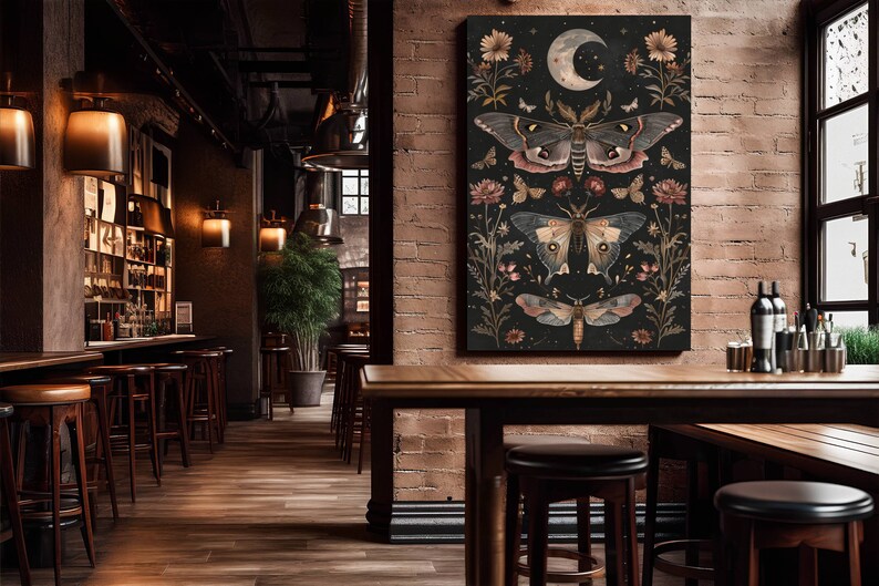 May include: A black canvas print with a dark background featuring three detailed illustrations of moths with intricate wings and a crescent moon with stars. The moths are surrounded by floral elements in shades of pink, red, and white.