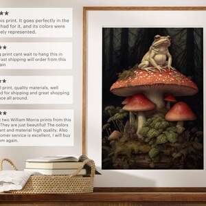 May include: A framed print of a frog sitting on a red mushroom in a dark forest setting. The print is surrounded by a wooden frame.
