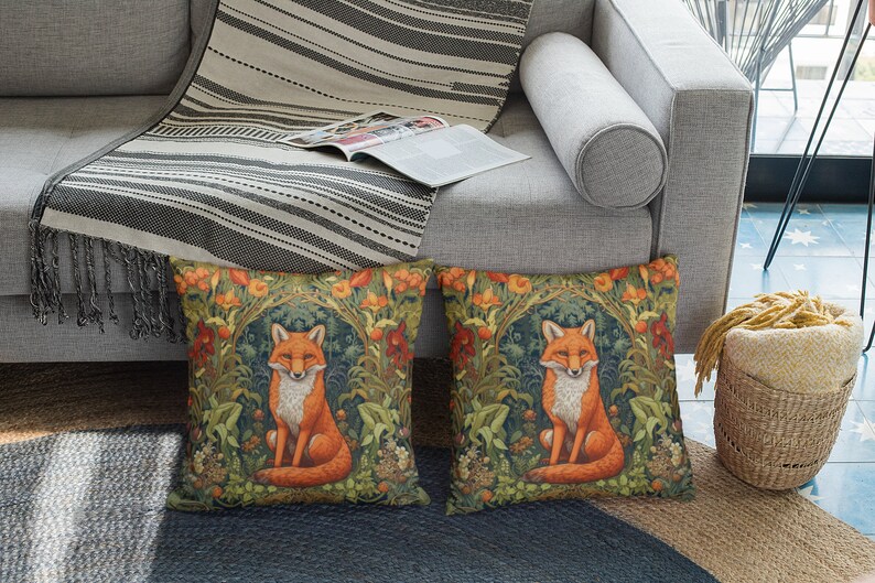 May include: Two decorative throw pillows with a fox illustration surrounded by flowers and greenery. The pillows are on a gray couch with a striped throw blanket.