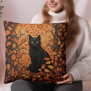May include: A black cat with yellow eyes sits in a forest of orange and brown leaves. The cat is surrounded by leaves and branches. The background is a blurred image of a forest.