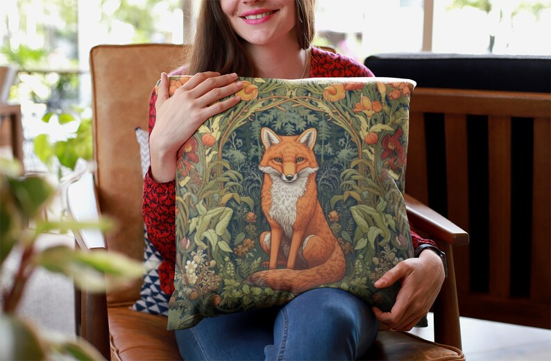 May include: A throw pillow with a green, orange, and brown fox illustration surrounded by floral designs. The fox is sitting in a forest setting with leaves and flowers.