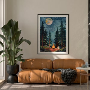 May include: A framed watercolor print depicts a nighttime camping scene. Tall evergreen trees surround a campfire with a tent in the background. A large moon hangs in the sky. The print is displayed above a brown leather sofa with a black blanket.