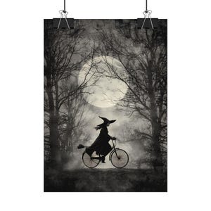 K&ouml;nnte beinhalten: Schwarz-Wei&szlig;-Poster mit einer Hexe auf einem Fahrrad mit einem Besen, vor einem Vollmond und einem Wald. Der Druck wird von zwei schwarzen B&uuml;roklammern gehalten. Das Bild hat ein Halloween-Thema.