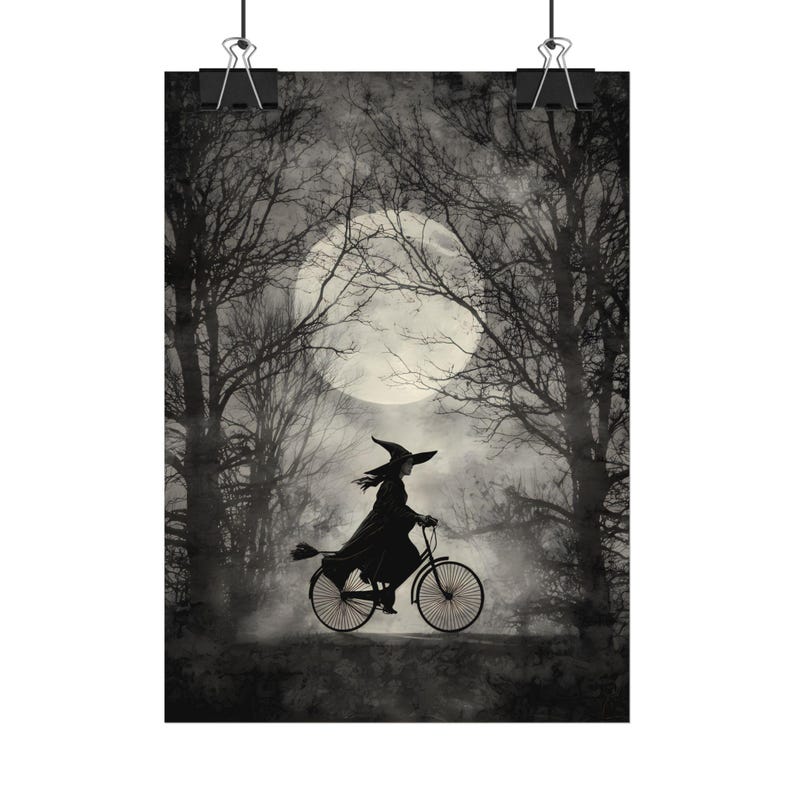 K&ouml;nnte beinhalten: Schwarz-Wei&szlig;-Poster mit einer Hexe auf einem Fahrrad mit einem Besen, vor einem Vollmond und einem Wald. Der Druck wird von zwei schwarzen B&uuml;roklammern gehalten. Das Bild hat ein Halloween-Thema.