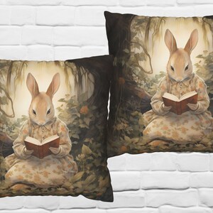 K&ouml;nnte beinhalten: Zwei Kissenbez&uuml;ge mit einer Waldszene, in der ein Kaninchen ein Kleid tr&auml;gt und ein Buch liest. Die Kissen haben einen dunkelbraunen Hintergrund mit gr&uuml;nem Laub und einem hellbraunen Kaninchen.