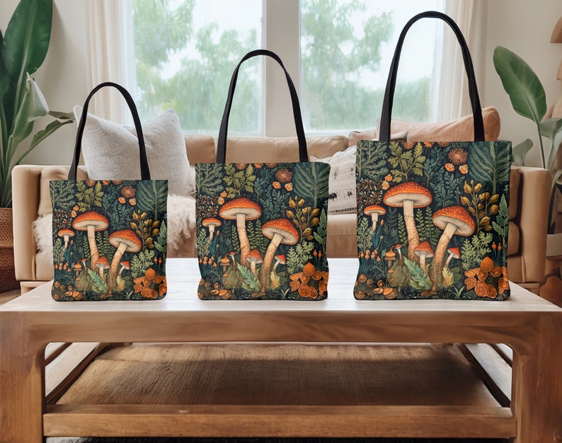 Puede incluir: Tres bolsas de mano con asas negras y un fondo verde bosque con setas naranjas y hojas verdes.
