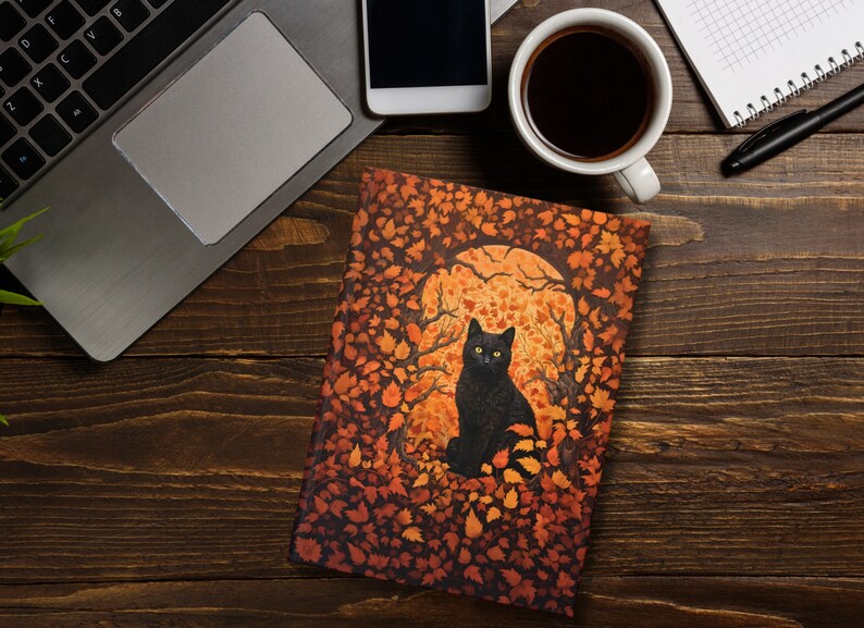 This William Morris inspired hardcover journal depicts a black cat with piercing yellow eyes surrounded by lush and gorgeous fall leaves in various shades or orange, yellow, and brown. The back cover is black with a small image in the center.