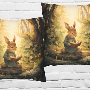May include: Two throw pillows with a woodland scene featuring a brown rabbit reading a book in a forest setting. The pillows have a soft, muted color palette with shades of brown, green, and yellow.