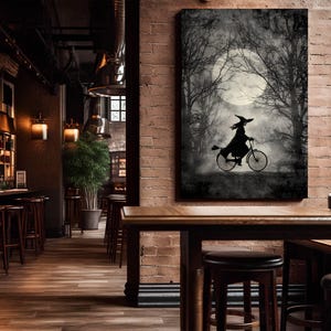 K&ouml;nnte beinhalten: Schwarz-Wei&szlig;-Kunstwerk einer Hexe auf einem Fahrrad in einem Wald unter einem Vollmond. Die Hexe ist eine Silhouette vor dem Mond, mit B&auml;umen im Hintergrund. Das Kunstwerk wird an einer Backsteinmauer ausgestellt.