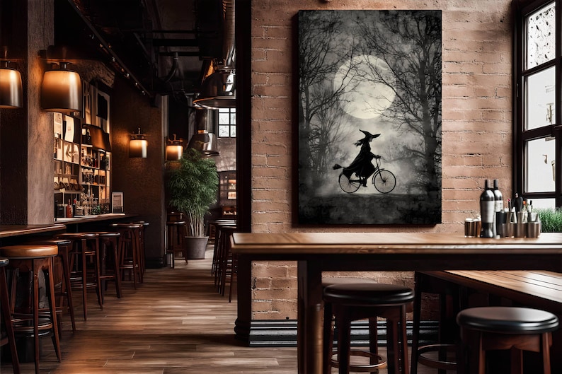 K&ouml;nnte beinhalten: Schwarz-Wei&szlig;-Kunstwerk einer Hexe auf einem Fahrrad in einem Wald unter einem Vollmond. Die Hexe ist eine Silhouette vor dem Mond, mit B&auml;umen im Hintergrund. Das Kunstwerk wird an einer Backsteinmauer ausgestellt.