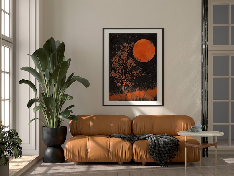 Peut inclure: Un canap&eacute; en cuir marron avec un plaid noir et blanc devant une impression encadr&eacute;e noire d'un arbre et d'une grande lune orange sur un fond sombre.